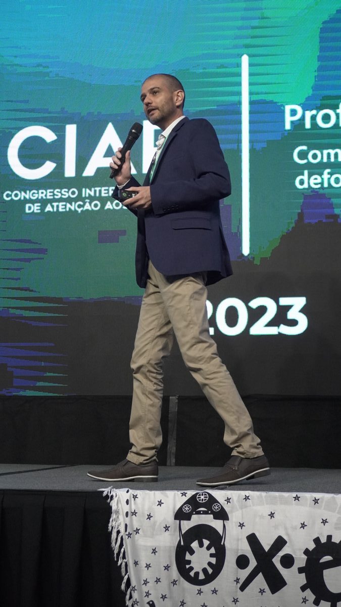 Palestrante no palco do CIAP 2023, com o painel do congresso ao fundo